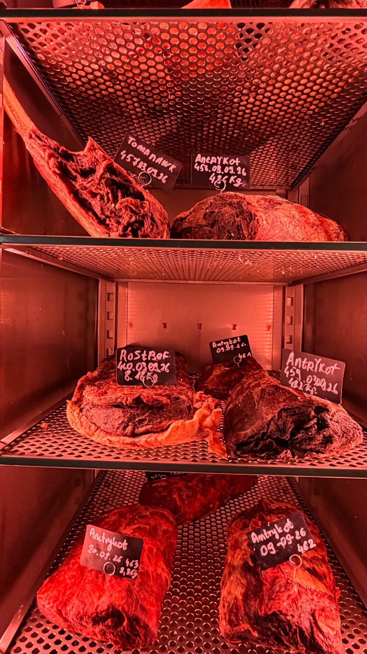 Półki szafy do sezonowania wołowiny w Amarone z tabliczkami daty i wagi